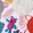 A flat lay of several different crocheted children's items including toys and clothing.