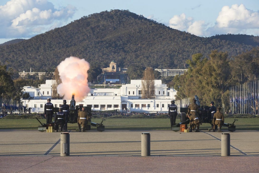 Military personnel conducting a cannon salute. Old Parliament House and Mount Ainslie are in the background.